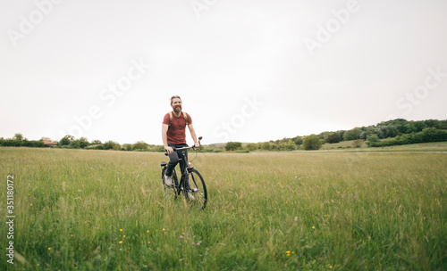 Bearded man riding bicycle in nature, copy space