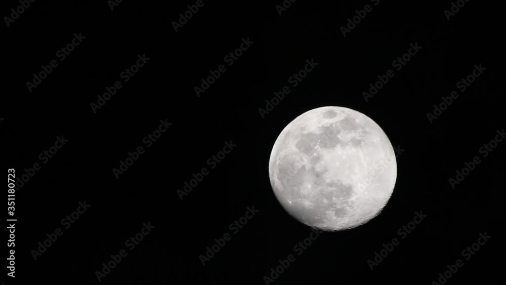 Very faint clouds passing in front of full moon. Great details seen on the moon surface and a brilliant contrast between dark sky and brightly illuminated moon. Very faint clouds passing in front of full moon. Great details seen on the moon surface and a brilliant contrast between dark sky and brightly illuminated moon.