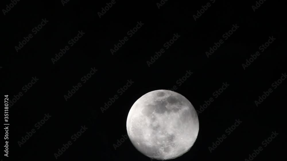 Very thin clouds starting out, pass by full moon, the moon starts at the very bottom of the frame and moves to the lower third by the end. Clouds begin to thicken in middle of clip but then dissipate. Very thin clouds starting out, pass by full moon, the moon starts at the very bottom of the frame and moves to the lower third by the end. Clouds begin to thicken in middle of clip but then dissipate.