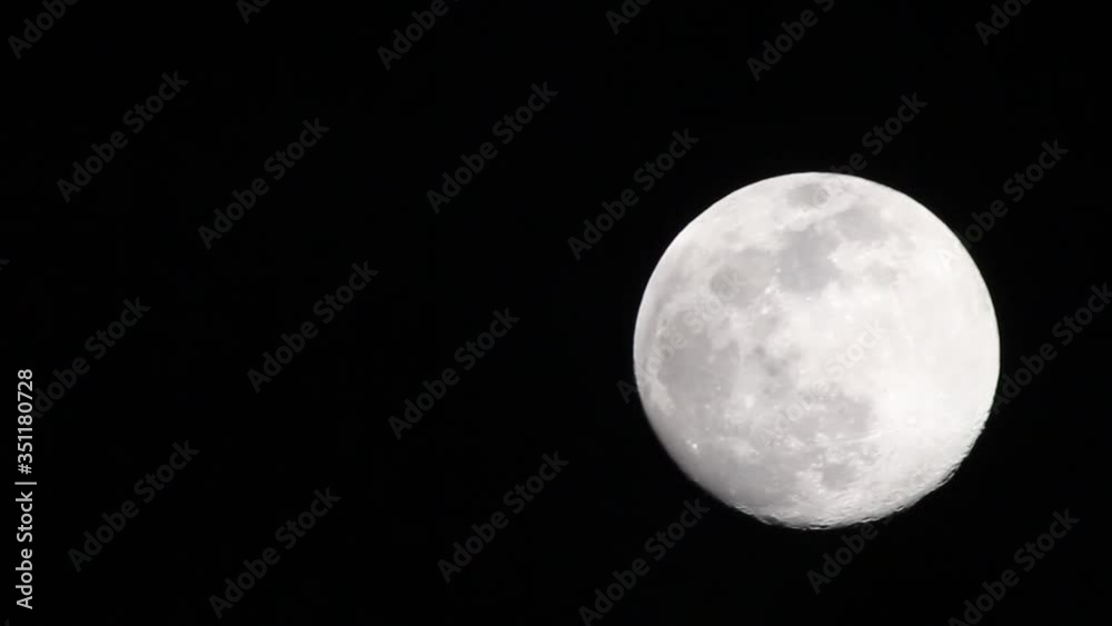 Starting very close to moon, slowly zooming away as thin clouds pass in front of it. Great details seen on the moon surface and a brilliant contrast between dark sky and brightly illuminated moon. Starting very close to moon, slowly zooming away as thin clouds pass in front of it. Great details seen on the moon surface and a brilliant contrast between dark sky and brightly illuminated moon.