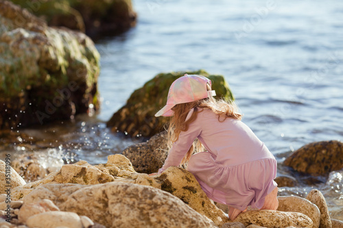 Happy pretty girl walks along the sea coast against the background of the sea  from behind a beautiful landscape