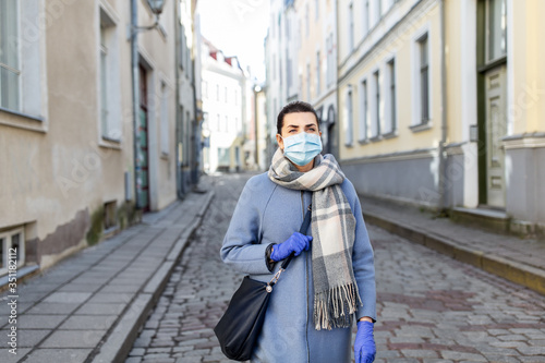 health, safety and pandemic concept - young woman wearing black face protective medical mask and gloves in city © Syda Productions