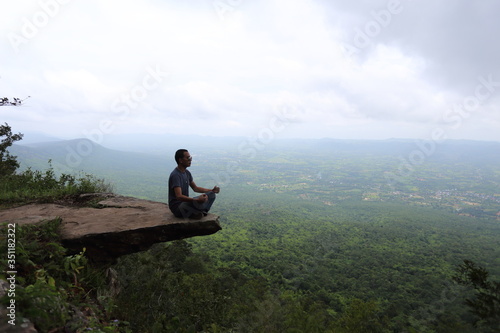 Man sitting at the edge of a cliff Sai Thong National Park in Chaiyaphum, Thailand.