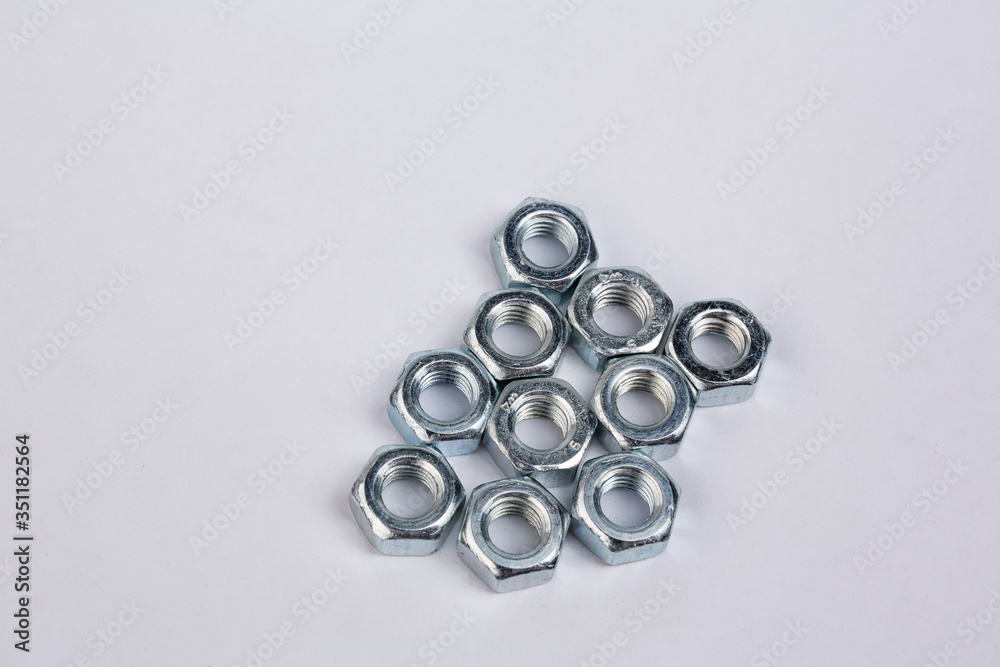 Several chrome nuts laid out on a white background. Close-up of repair parts Several chrome nuts laid out on a white background. Close-up of repair parts