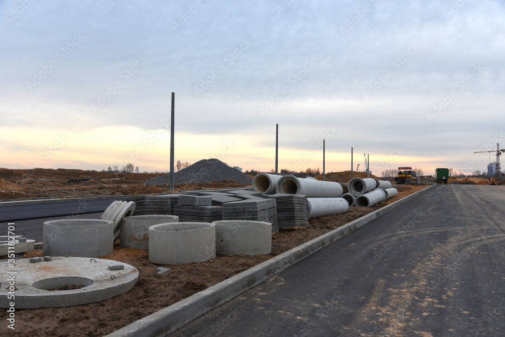 Concrete drainage pipes at the construction site. Laying of underground storm sewer pipes. Installation of water main, sanitary sewer. Installation of concrete sewer wells in the ground