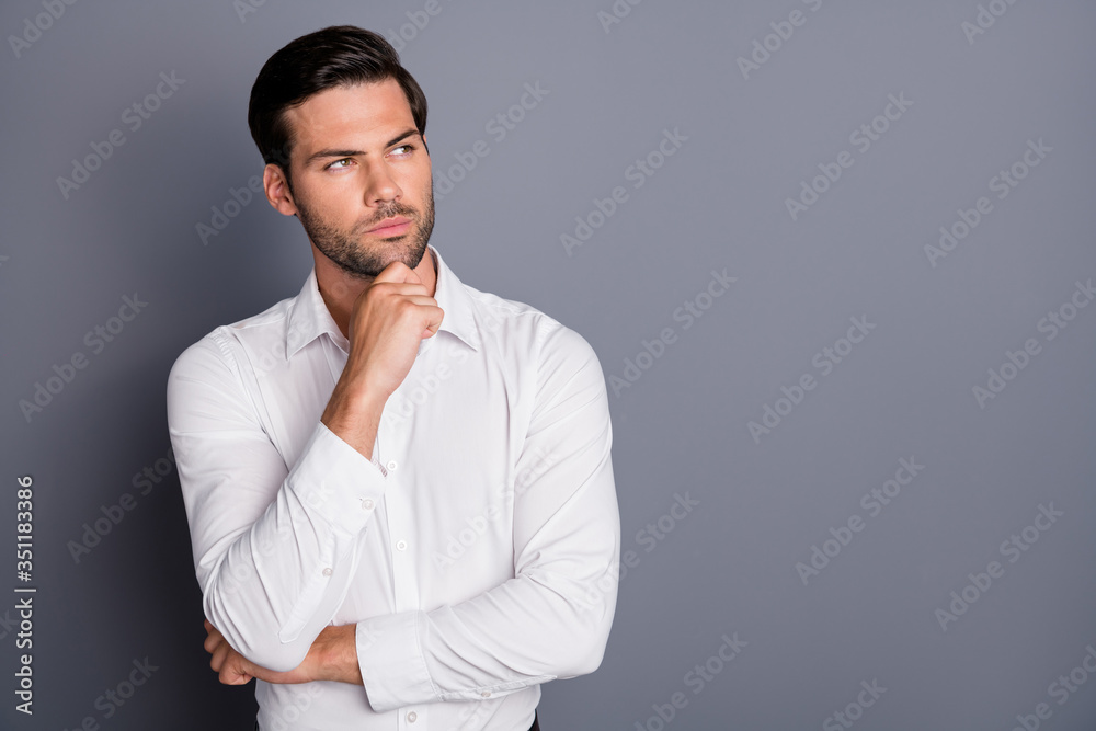 Photo of young business man employer hold arm on chin look curious empty space not smiling think over startup smart person wear white office shirt isolated grey color background Photo of young business man employer hold arm on chin look curious empty space not smiling think over startup smart person wear white office shirt isolated grey color background