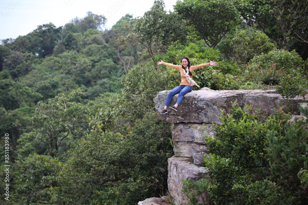 Woman sitting on a cliff at Mor Hin Khao National Park in Chaiyaphum, Thailand