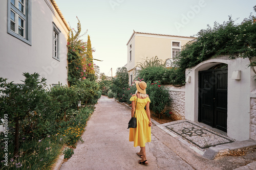 Young traveling woman in hat and yellow dress walking on old town enjoying the view. photo