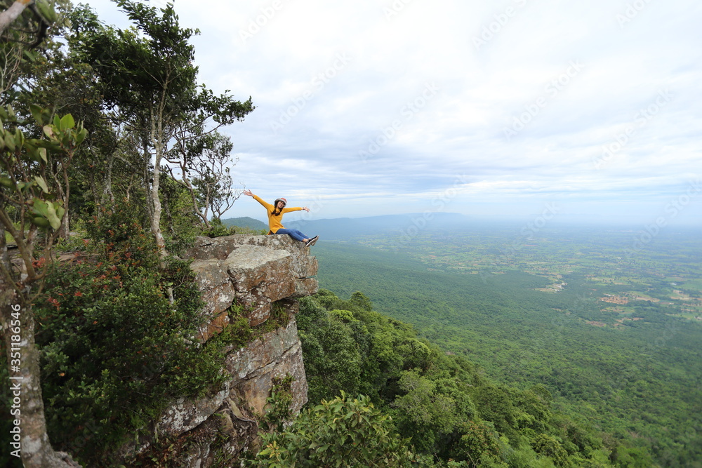 Woman sitting on a cliff at Mor Hin Khao National Park in Chaiyaphum, Thailand