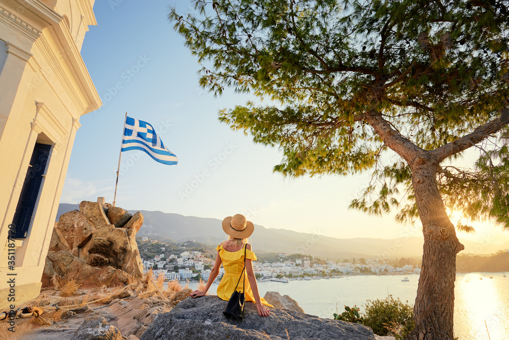 Fototapeta premium Vacation in Greece. Young traveling woman enjoying sunset on sea on Poros tower view point.