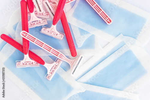 Pink disposable razor blades and hair removal strips isolated on white. Beauty, hair removal and woman care concept. Plastic waste.