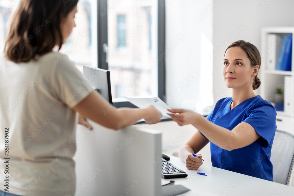 Obraz premium medicine, people and healthcare concept - female doctor or nurse and patient with prescription at hospital