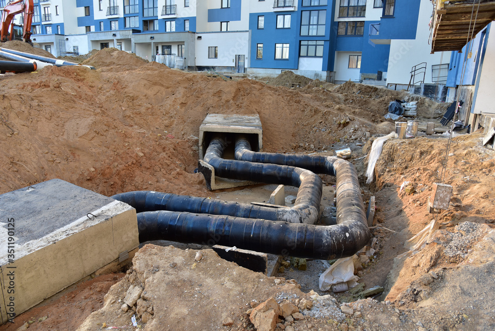 Laying heating pipes in a trench at construction site. Install underground storm systems of water main and sanitary sewer. Cold and hot water, heating and heating system of apartments in the house