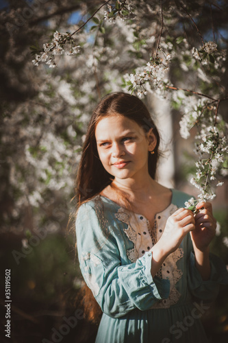 beautiful young girl with long flowing hair in a blooming cherry blossoms garden