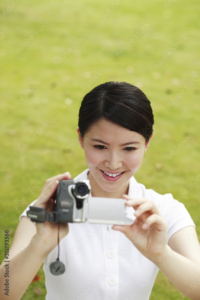 Woman using video camera in the park Woman using video camera in the park