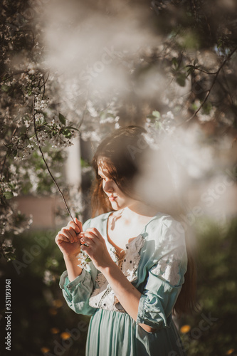 beautiful young girl with long flowing hair in a blooming cherry blossoms garden