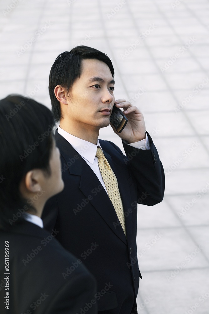 Businessman talking on the phone with his partner standing by his side Businessman talking on the phone with his partner standing by his side