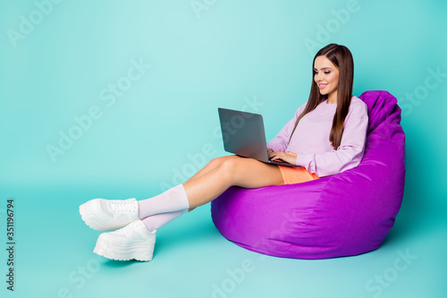 Full body profile photo of charming lady sit comfy bean bag chair hold notebook freelance working wear purple sweater orange skirt sneakers socks isolated teal color background