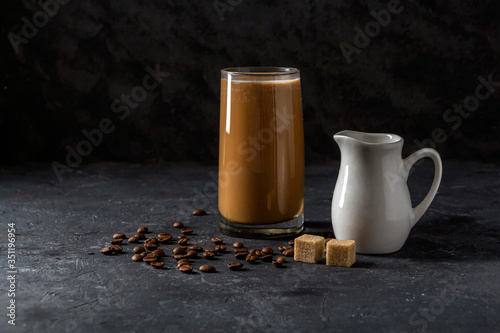 Ice coffee frappe in tall glass. Cool summer drink on a dark background in low key. Close up, copy space for text