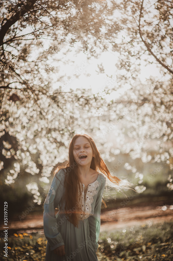 beautiful young girl with long flowing hair in a blooming cherry blossoms garden beautiful young girl with long flowing hair in a blooming cherry blossoms garden