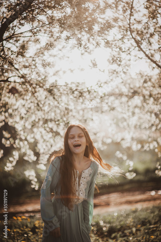 beautiful young girl with long flowing hair in a blooming cherry blossoms garden