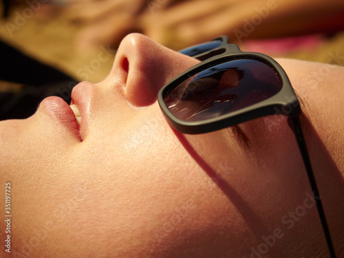 Face portrait of a girl in sunglasses on the beach