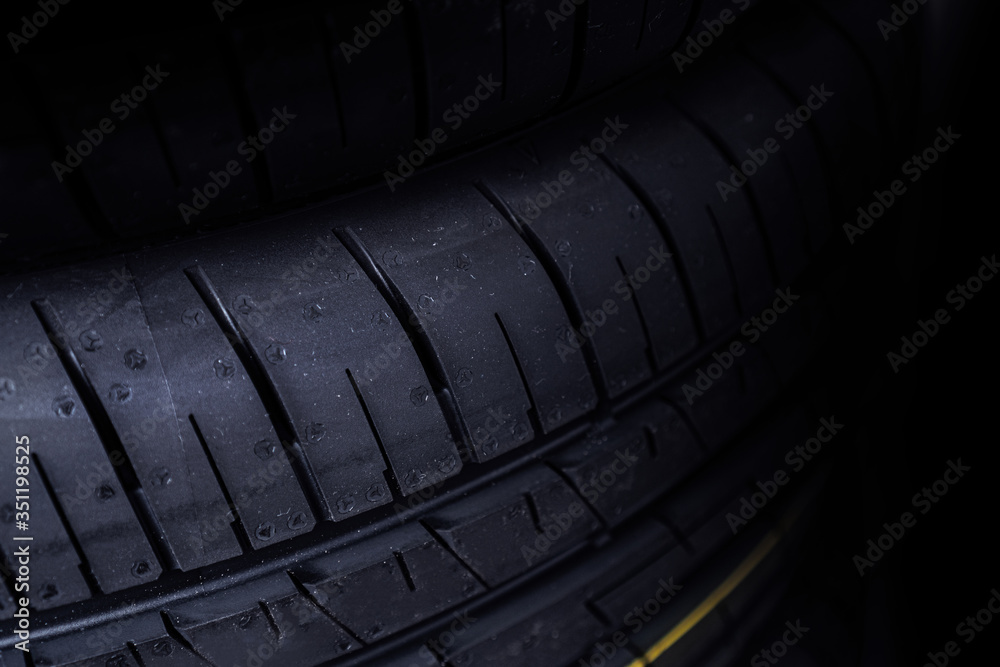 New tire background. Fragment of tyre on the dark background.