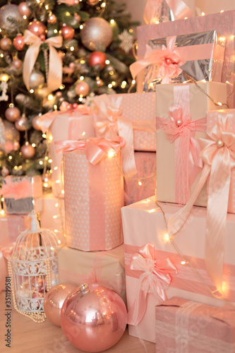 Beautiful festive decorated pink room with a Christmas tree with gifts under it.