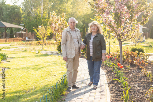 Active seniors on a walk in summer park, senior couple relax in spring summer time. Healthcare lifestyle elderly retirement love couple together valentines day concept