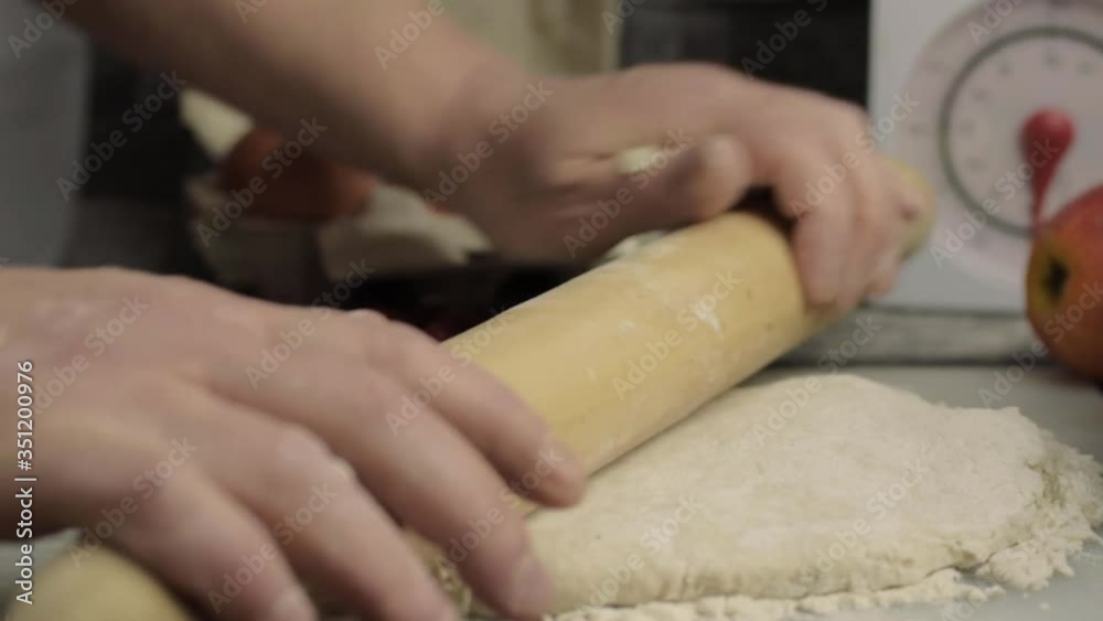 Hands using rolling pin in kitchen to roll dough medium shot Hands using rolling pin in kitchen to roll dough medium shot