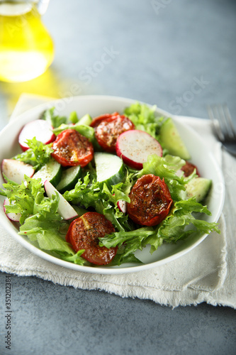 Healthy green salad with sun dried tomatoes, radish, cucumber