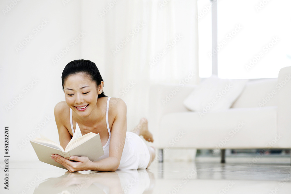 Woman lying forward on the floor, reading book Woman lying forward on the floor, reading book