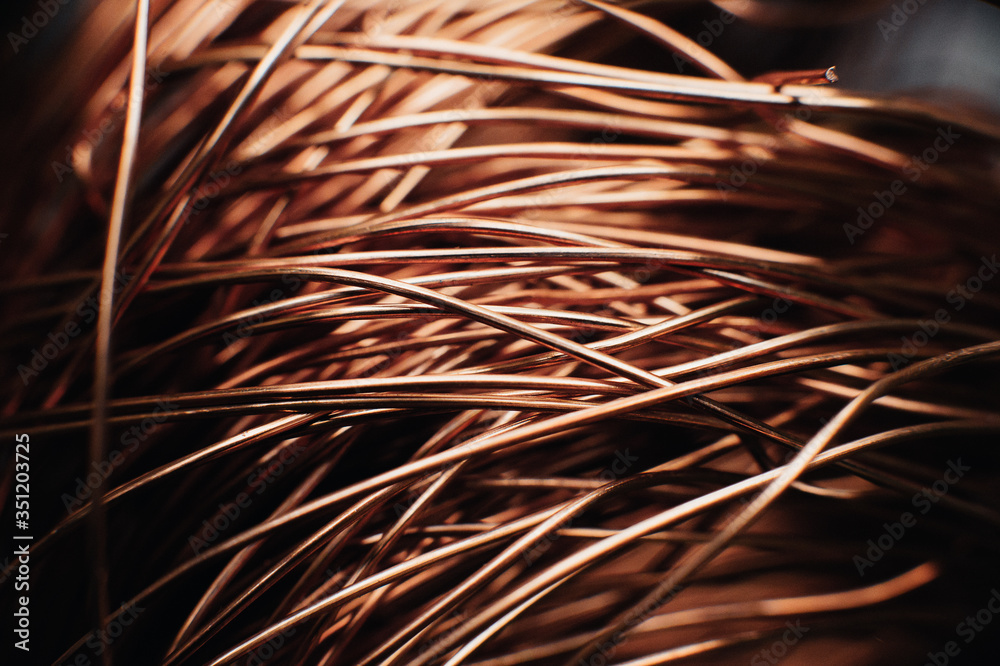 Fototapeta premium Copper scrap metal, wire, windings of motors and transformers, electrical wire without insulation. Against the background of a copper sheet. Close-up. Macro.