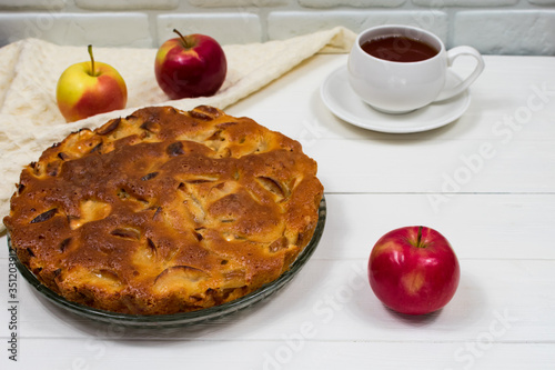 Homemade baked apple pie, in a plate, on a white wooden table, ready to eat. Place for an inscription...