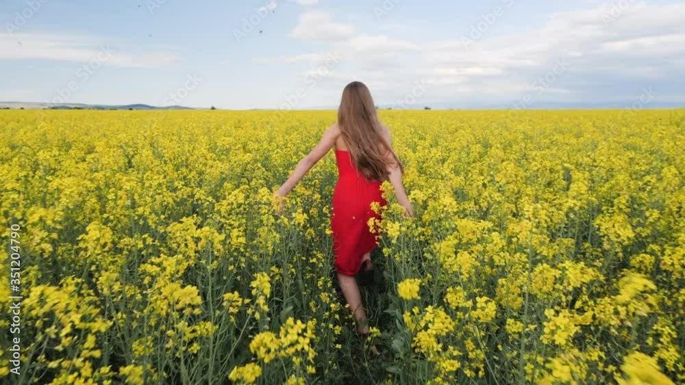 Young girl running through canola field - camera follow through the field, slow motion Young girl running through canola field - camera follow through the field, slow motion
