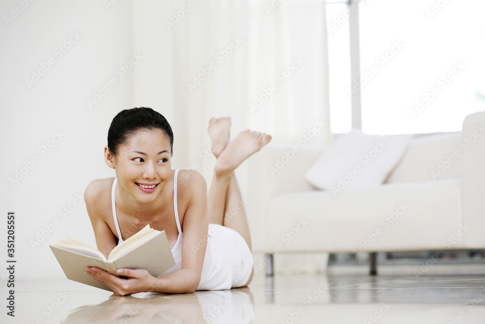 Woman lying forward on the floor reading book Woman lying forward on the floor reading book