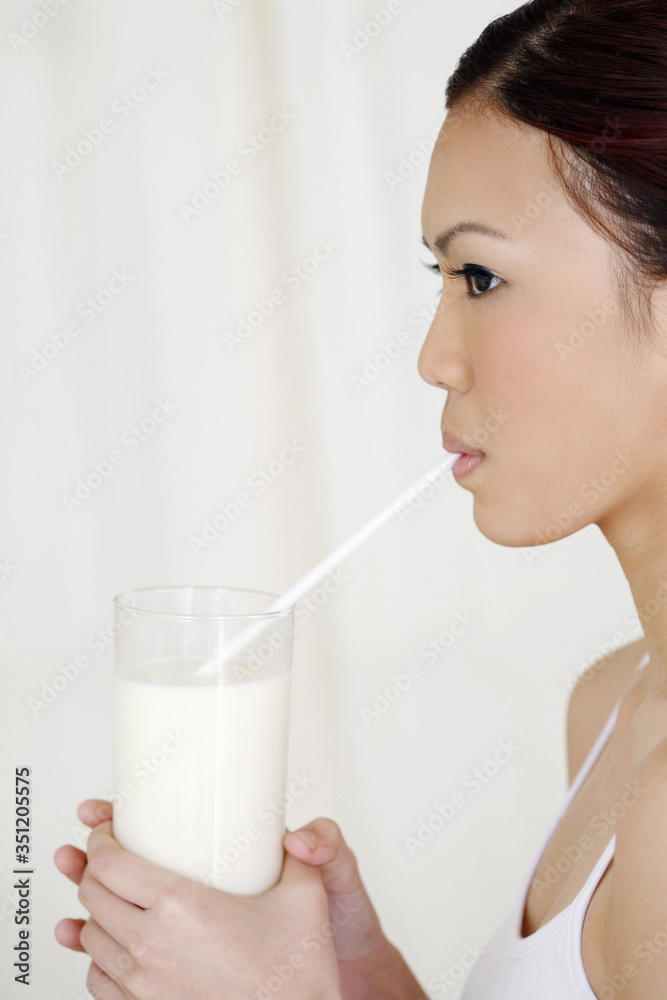 Woman drinking a glass of milk with drinking straw Woman drinking a glass of milk with drinking straw