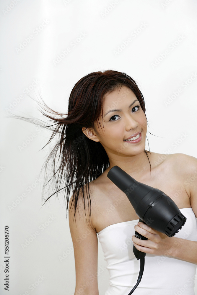 Woman blow-drying her hair with hair dryer Woman blow-drying her hair with hair dryer