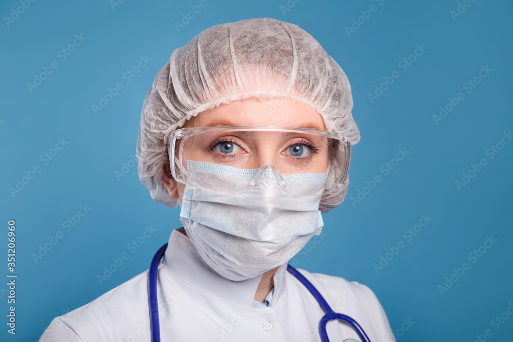 Female doctor or nurse wearing protective mask and goggles on blue background