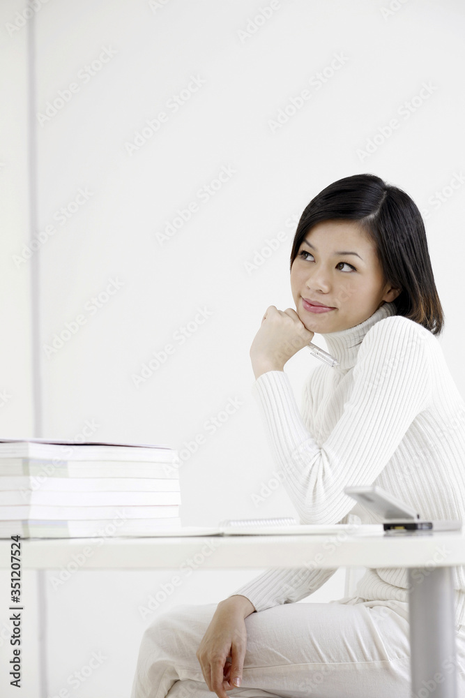 Woman thinking before writing on her notepad Woman thinking before writing on her notepad