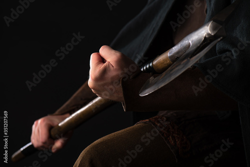 cropped view of medieval Scottish warrior with battle axe in hands isolated on black