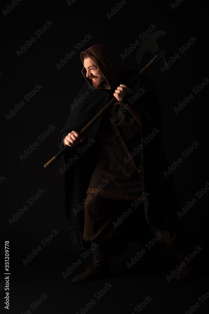 smiling medieval Scottish warrior with battle axe in mantel isolated on black smiling medieval Scottish warrior with battle axe in mantel isolated on black