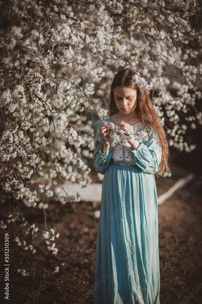 beautiful young girl with long flowing hair in a blooming cherry blossoms garden beautiful young girl with long flowing hair in a blooming cherry blossoms garden
