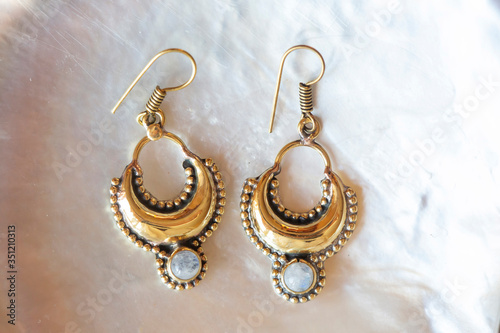 Brass pair of earrings in oriental style on white shell background