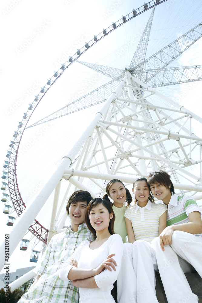Men and women smiling at the camera, Ferris wheel in the background Men and women smiling at the camera, Ferris wheel in the background
