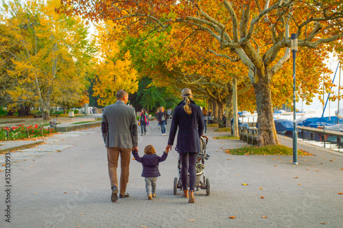 parents with a kid with baby carriage are walking holding hands in autumn park Zurich Switzerland October 26 2018