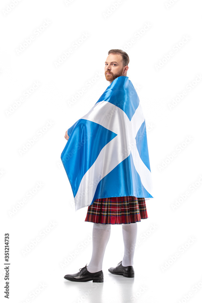 back view of Scottish redhead man in red kilt with flag of Scotland on white background back view of Scottish redhead man in red kilt with flag of Scotland on white background