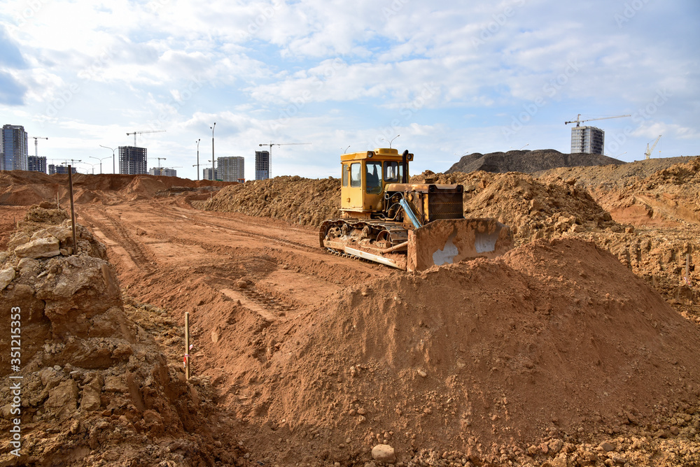 Dozer during roadwork at construction site. Bulldozer for land clearing, grading, pool excavation, utility trenching and foundation digging. Heavy machinery for earth-moving Dozer during roadwork at construction site. Bulldozer for land clearing, grading, pool excavation, utility trenching and foundation digging. Heavy machinery for earth-moving