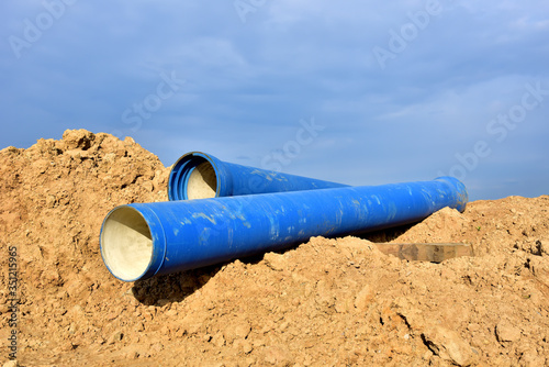 Blue concrete drainage pipes at the construction site. Laying of underground storm sewer pipes. Installation of water main, sanitary sewer. Installation of concrete sewer wells in the ground