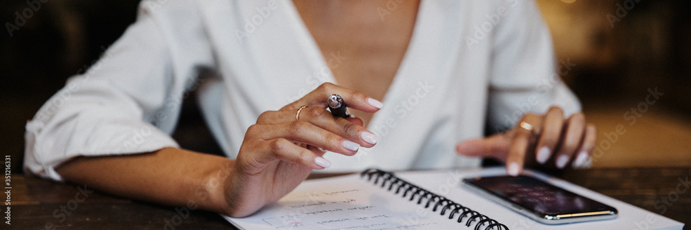Woman writing down on her notebook - obrazy, fototapety, plakaty 